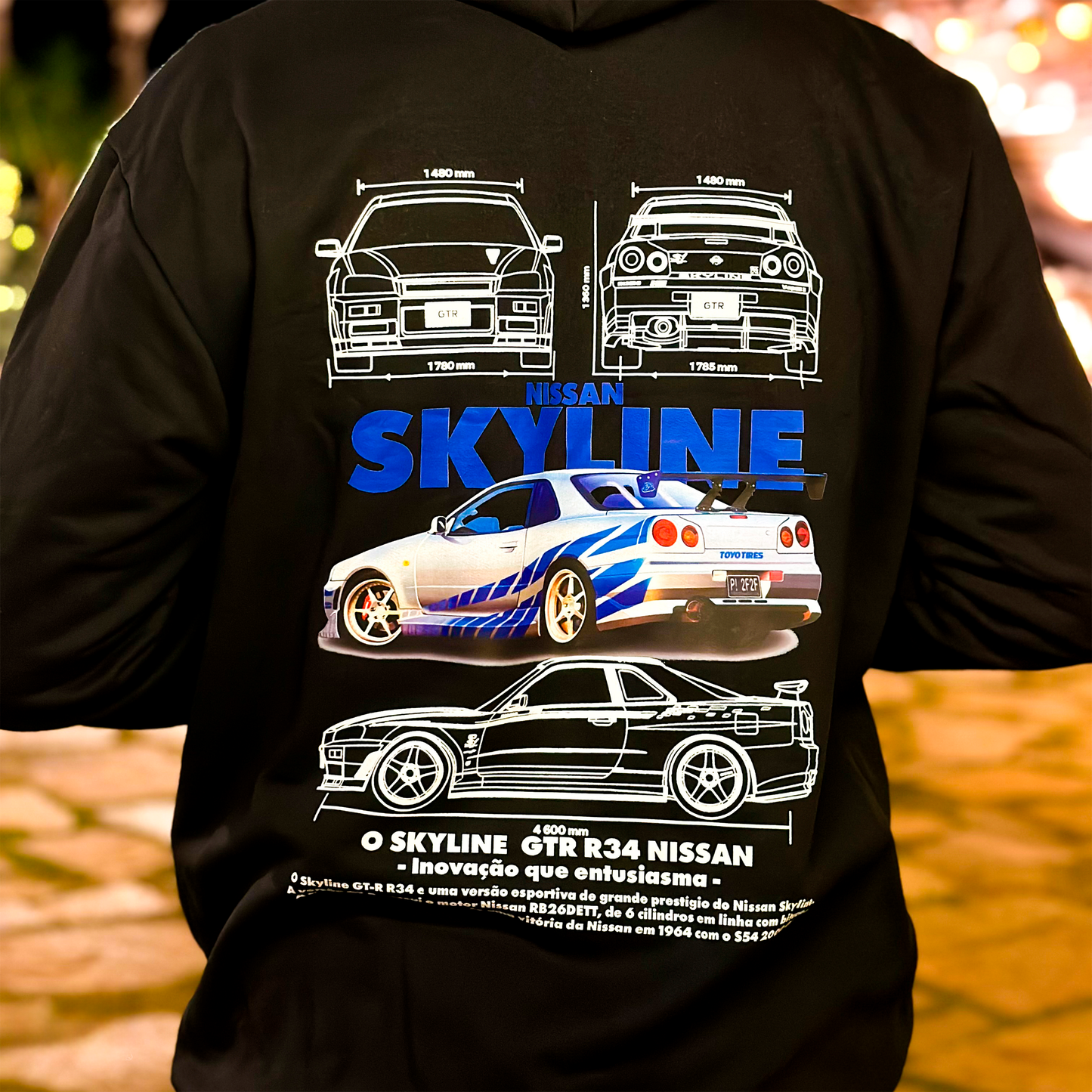 Black and white hoodies featuring the Nissan Skyline GT-R R34 blueprint design with technical views of the car and bold blue “SKYLINE” typography.