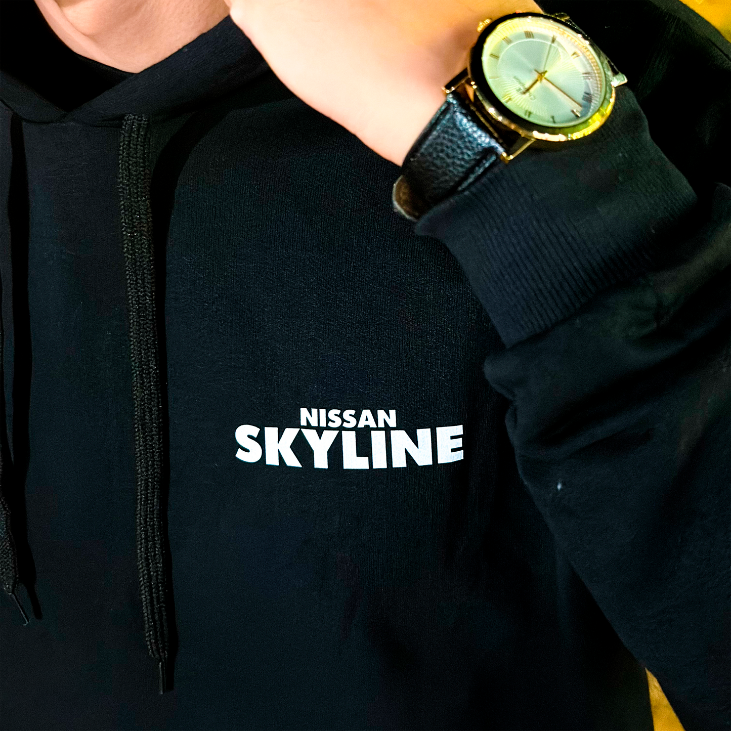Black and white hoodies featuring the Nissan Skyline GT-R R34 blueprint design with technical views of the car and bold blue “SKYLINE” typography.