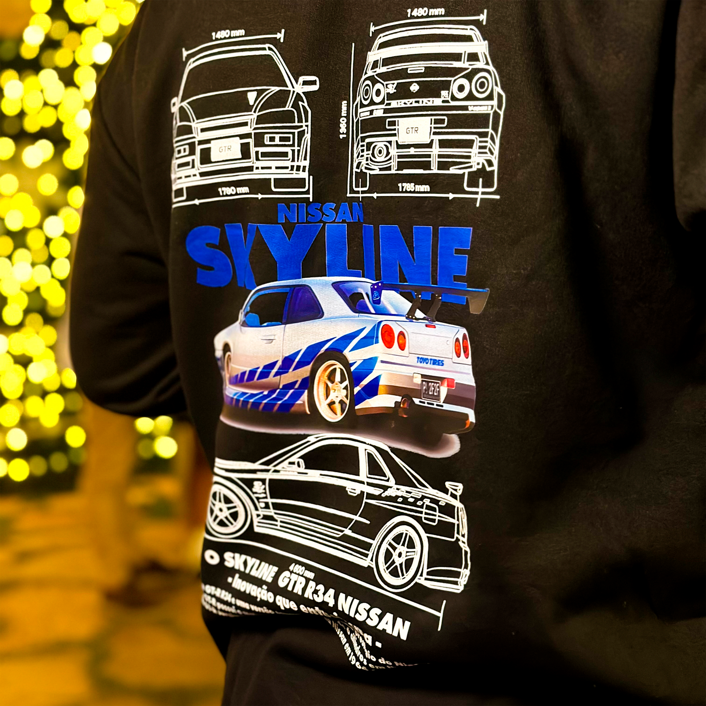 Black and white hoodies featuring the Nissan Skyline GT-R R34 blueprint design with technical views of the car and bold blue “SKYLINE” typography.