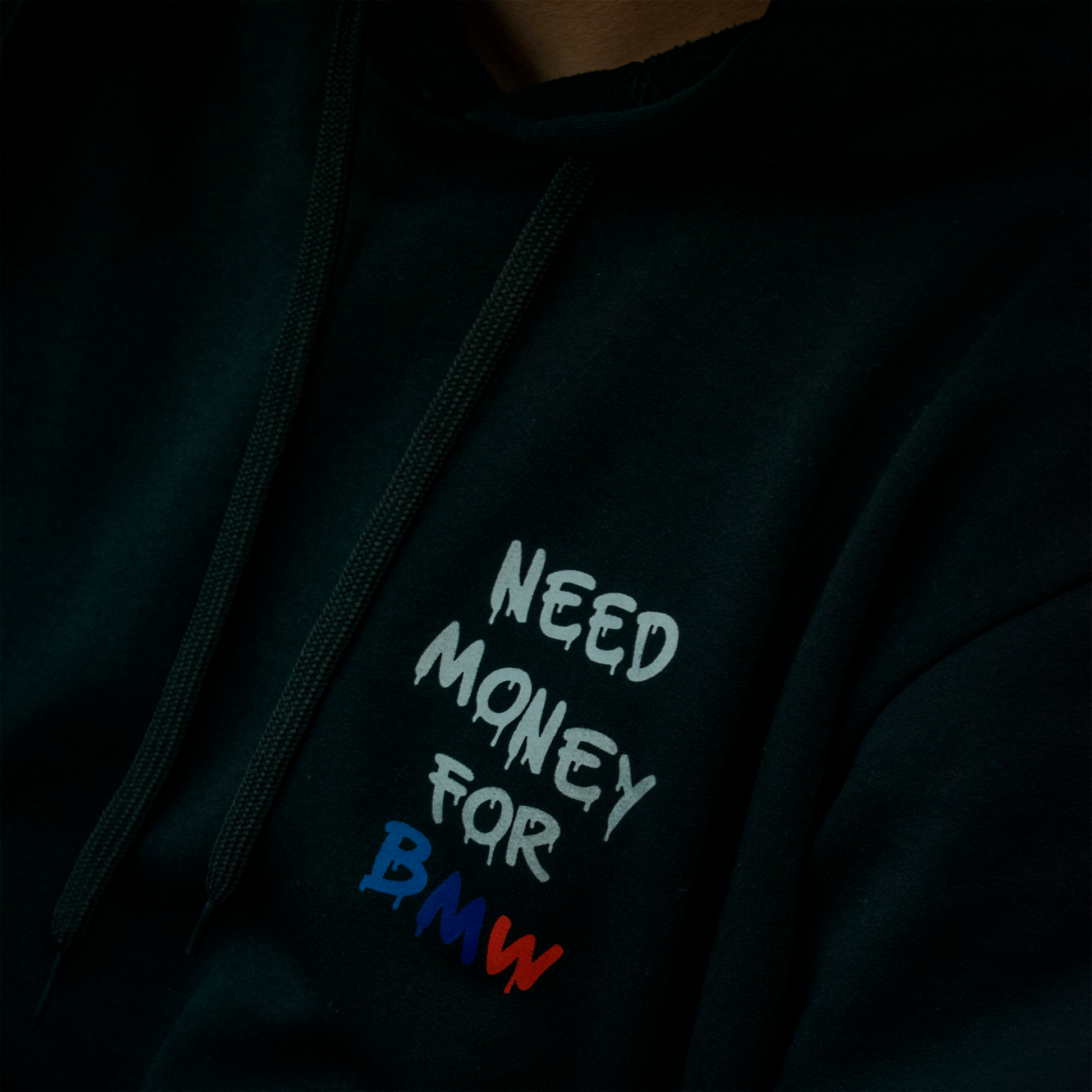 Black and white hoodies with the phrase “Need Money for BMW” in bold graffiti-style letters, featuring BMW M colors (blue, navy, and red) on the back and chest.